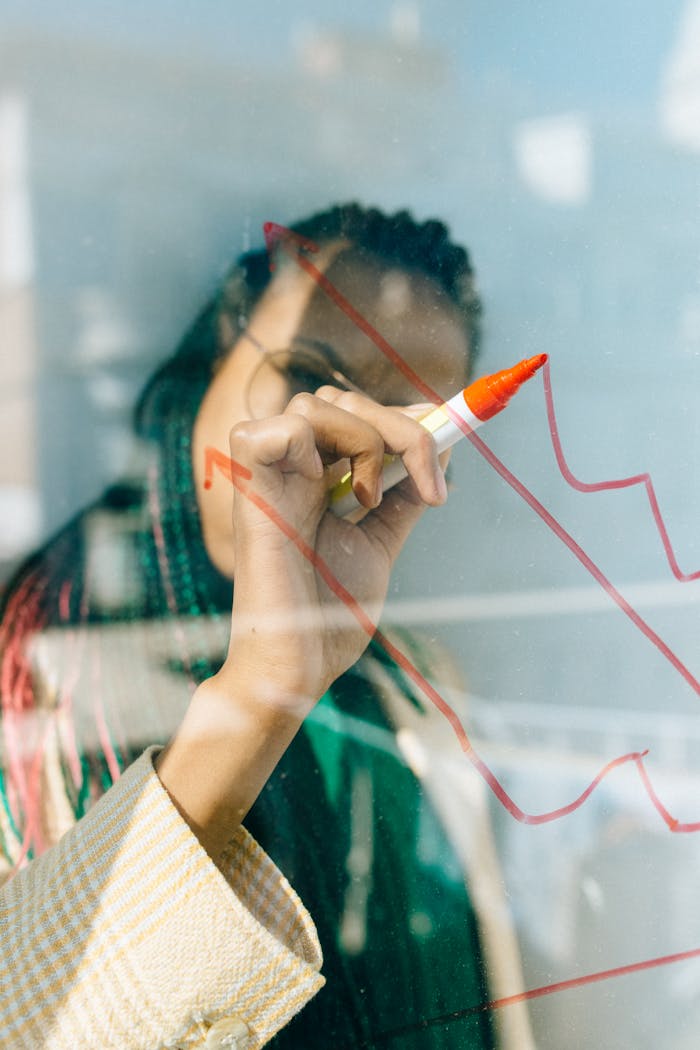 services-02 A businesswoman draws a red financial graph on a glass panel, symbolizing strategy and success.