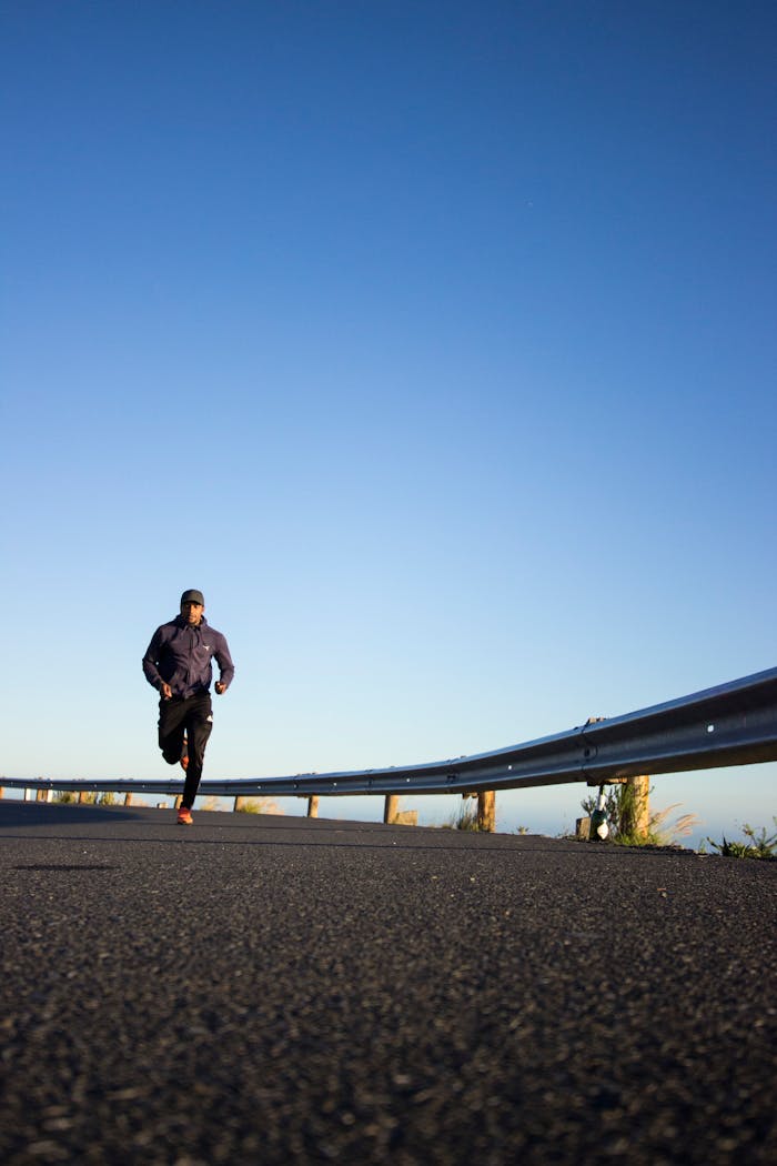 creative An athletic man jogging on an open road with a clear blue sky in Cape Town, South Africa.