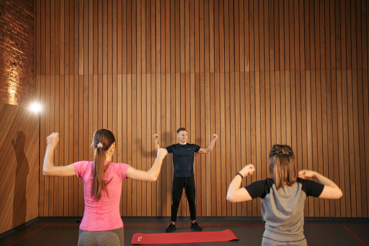 Services-01 Instructor guiding two women in a gym workout session. Indoor fitness training.